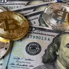 Złote i srebrne monety Bitcoin leżą na banknotach dolarowych. To obraz, który inspiruje do refleksji nad przyszłością pieniędzy i cytatami o finansach.
