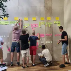 Zespół pracuje nad rozwojem organizacji, przyklejając karteczki z zadaniami na ścianie.