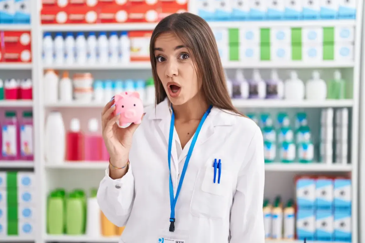 Farmaceutka z zaskoczoną miną trzyma skarbonkę. Czyżby zarobki osoby wykwalifikowanej nie były takie, jak się spodziewała?