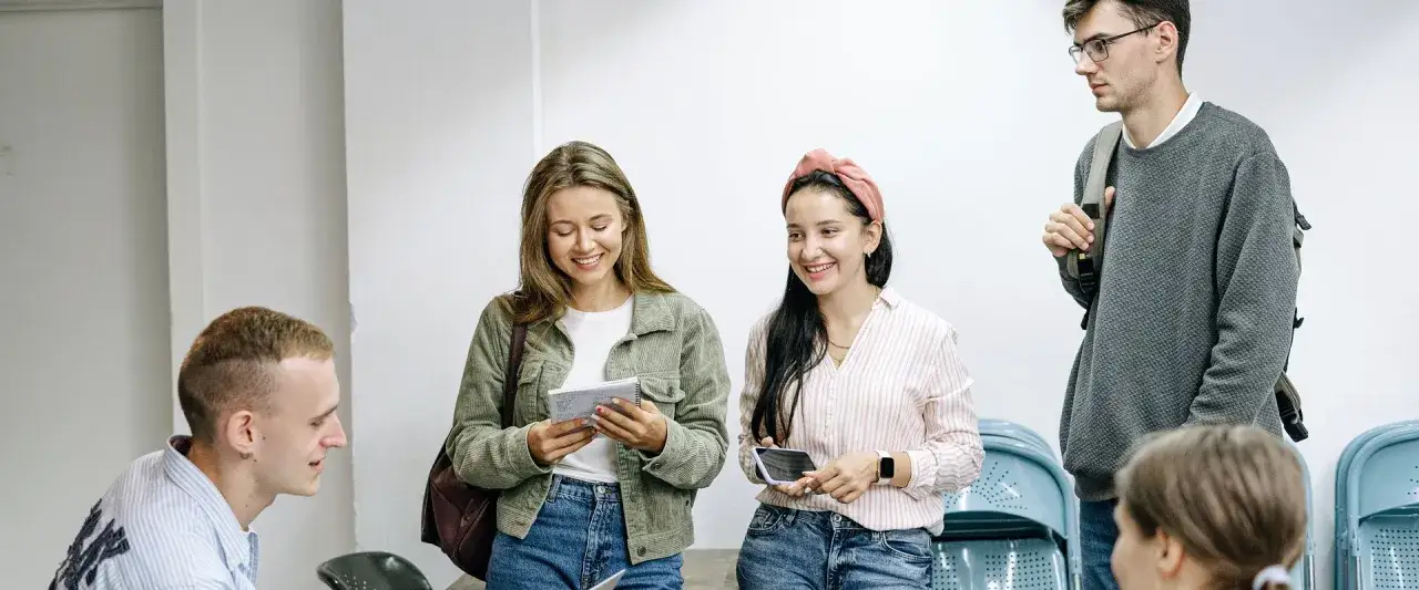 Studenci rozmawiają o tym, jak zdobyć doświadczenie zawodowe. Jedna z dziewczyn trzyma notatnik, druga telefon.